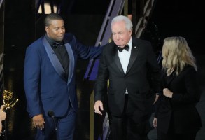 舞台上，两名西装革履的男子和一名女子对着麦克风;图为第74届艾美奖颁奖典礼。